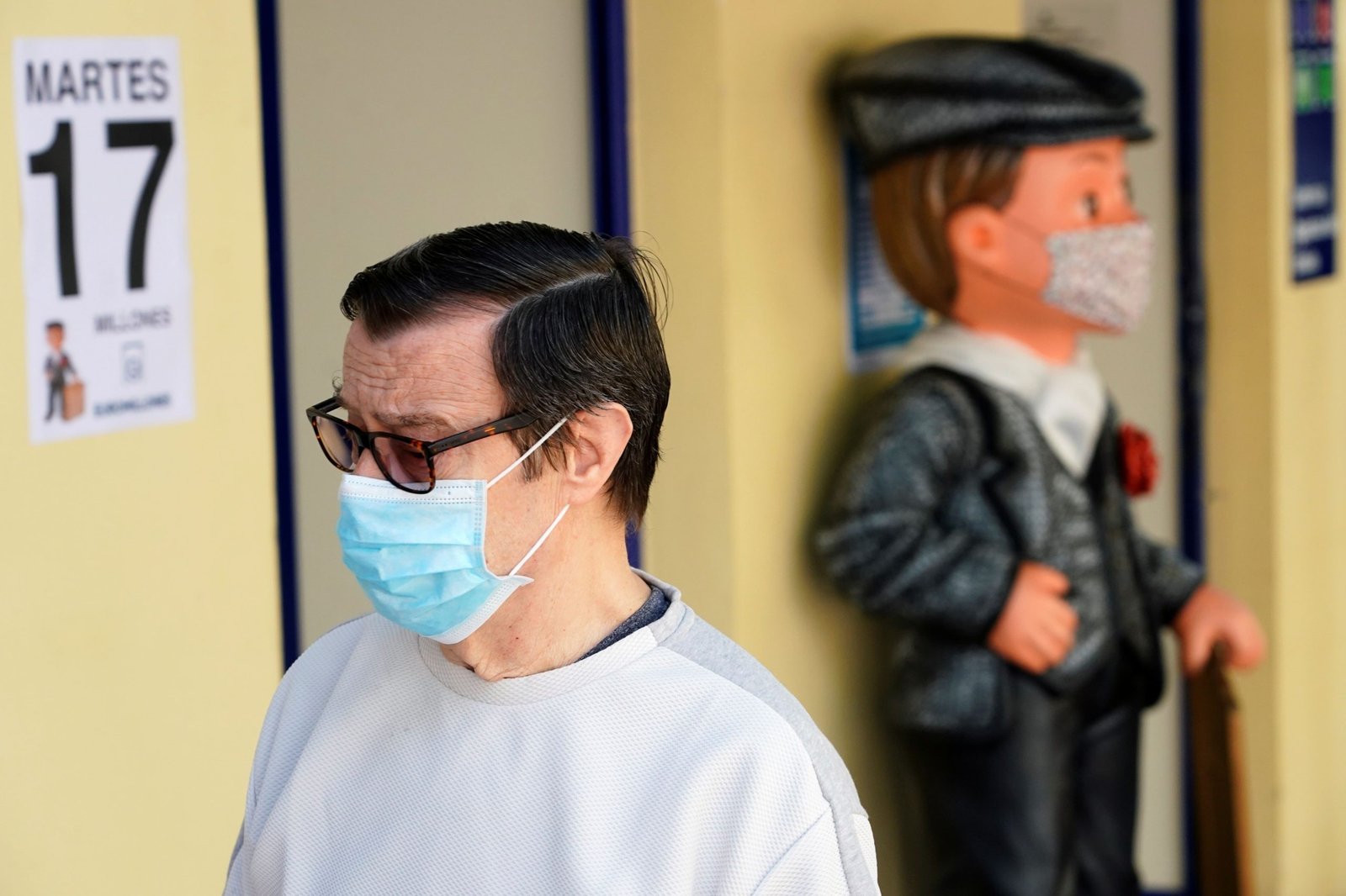 Un hombre junto a una estatua con la vestimenta tradicional de "Chulapo", ambos con mascarilla, en Madrid (Reuters)