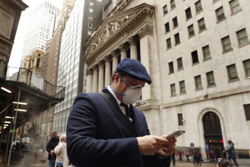 FOTO DE ARCHIVO. Un hombre revisa su celukar mientras pasa frente al edificio de la bolsa de Nueva York. Marzo, 2020