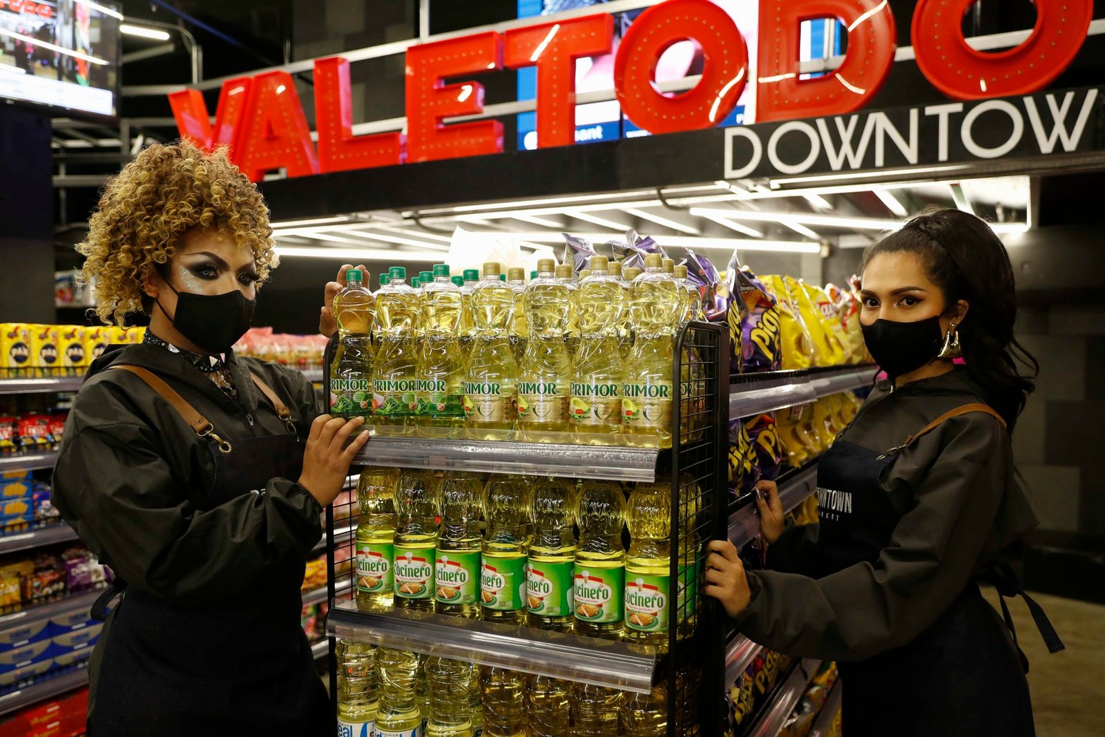 Las "drag queens" Belaluh (i) y Shamcey (d) que trabajaban en la discoteca gay más famosa de Lima, Downtown Vale Todo, ahora atienden al público en el supermercado que ocupa los 2.000 metros cuadrados del lugar. (EFE/Paolo Aguilar)