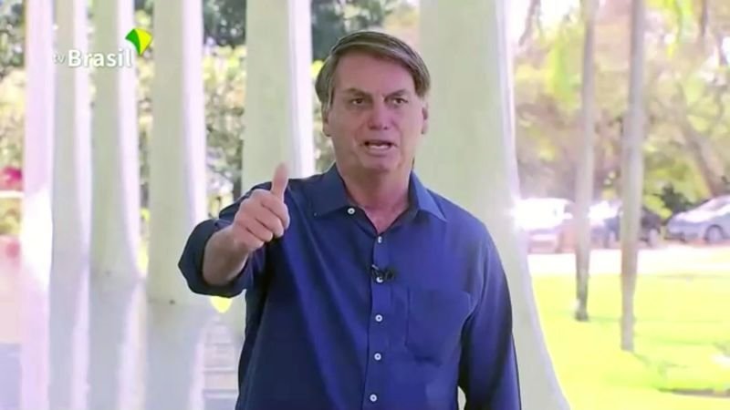 El presidente de Brasil, Jair Bolsonaro, se quita la mascarilla mientras habla a los medios sobre su diagnóstico positivo de coronavirus, en Brasilia, Brasil. 7 de julio de 2020. (TV Brasil vía Reuters TV)