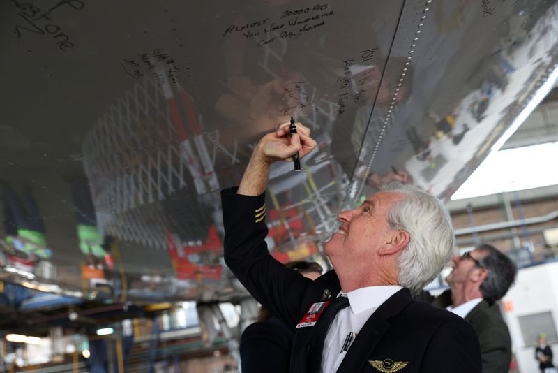 Un piloto de Qantas escribe un mensaje en la parte inferior de un jumbo Qantas 747 en el aeropuerto de Sídney, Australia, el 22 de julio de 2020.  REUTERS/Loren Elliott